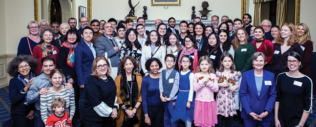 A very large group poses in an ornate roon